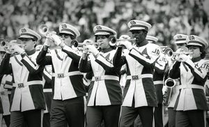 A row of band members perform in their 1970s uniforms.