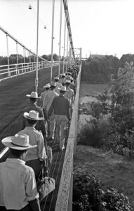 Long line of men crossing a bridge.