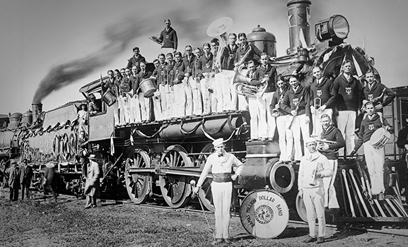 Members of the 1925 Million Dollar Band standing on and in front of a steam train.