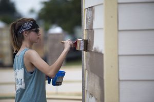 Young woman painting a building
