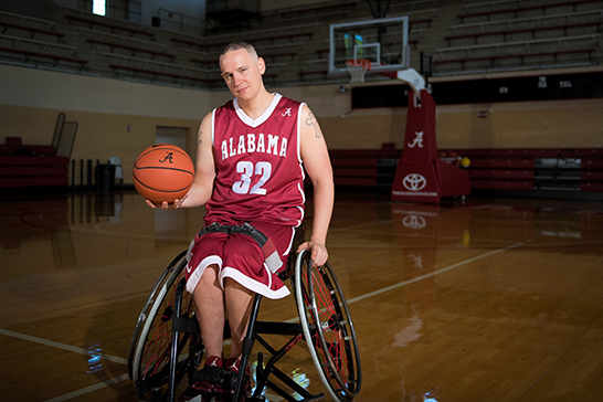 a young man in a wheelchair holding a basketball
