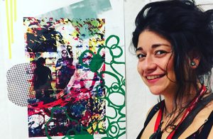 a young woman standing next to one of her art works, a colorful screen print