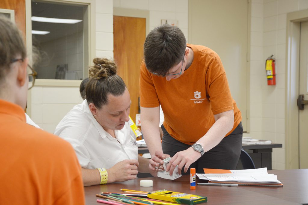 A teacher in the Prison Arts program helps a student participate in the class.