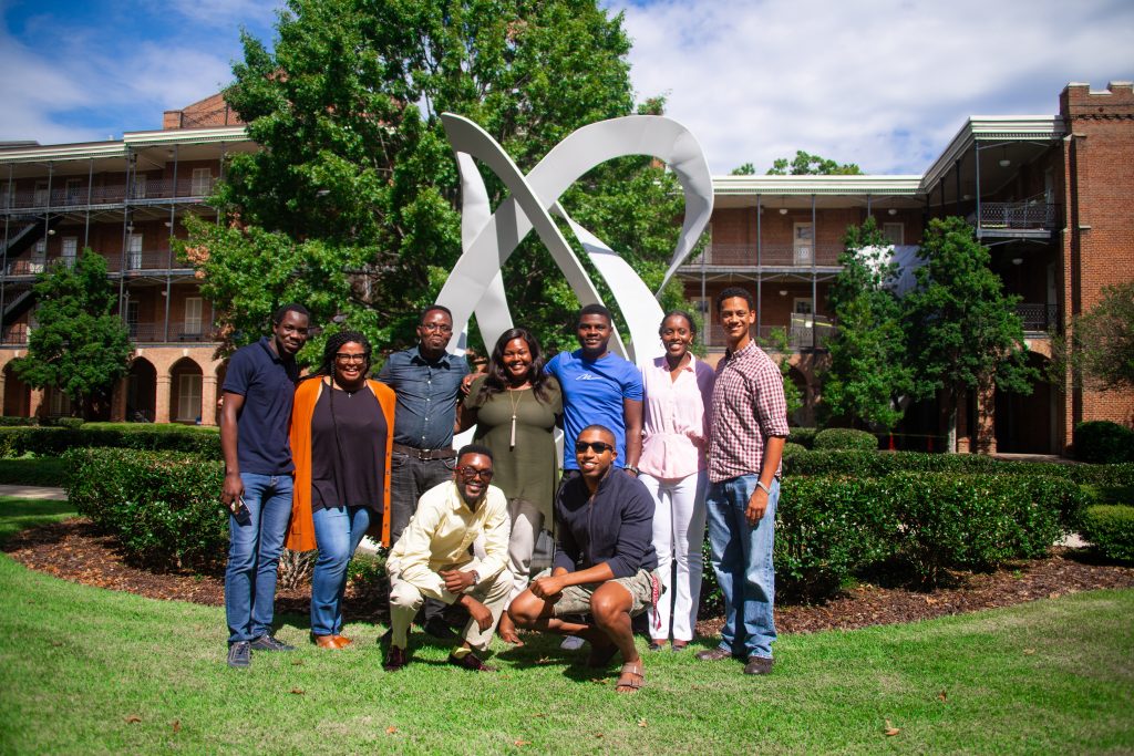 Some of the math graduate students in front of a sculpture in Woods Quad.