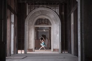 a dancer in a blue ballet costume dances in a pre-renovated building