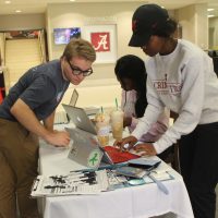 A student helps another student register to vote at a table.