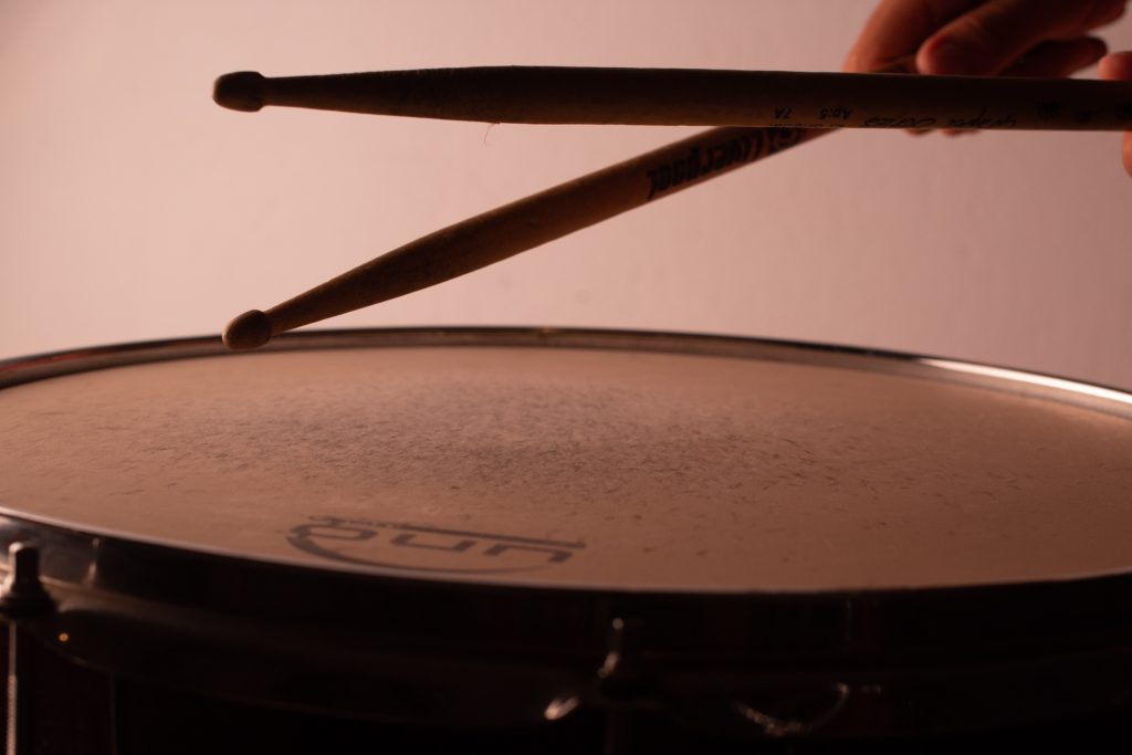 A drummer using sticks on a drum.