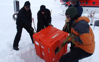 researchers in Antarctica lower equipment into a hole in the ice
